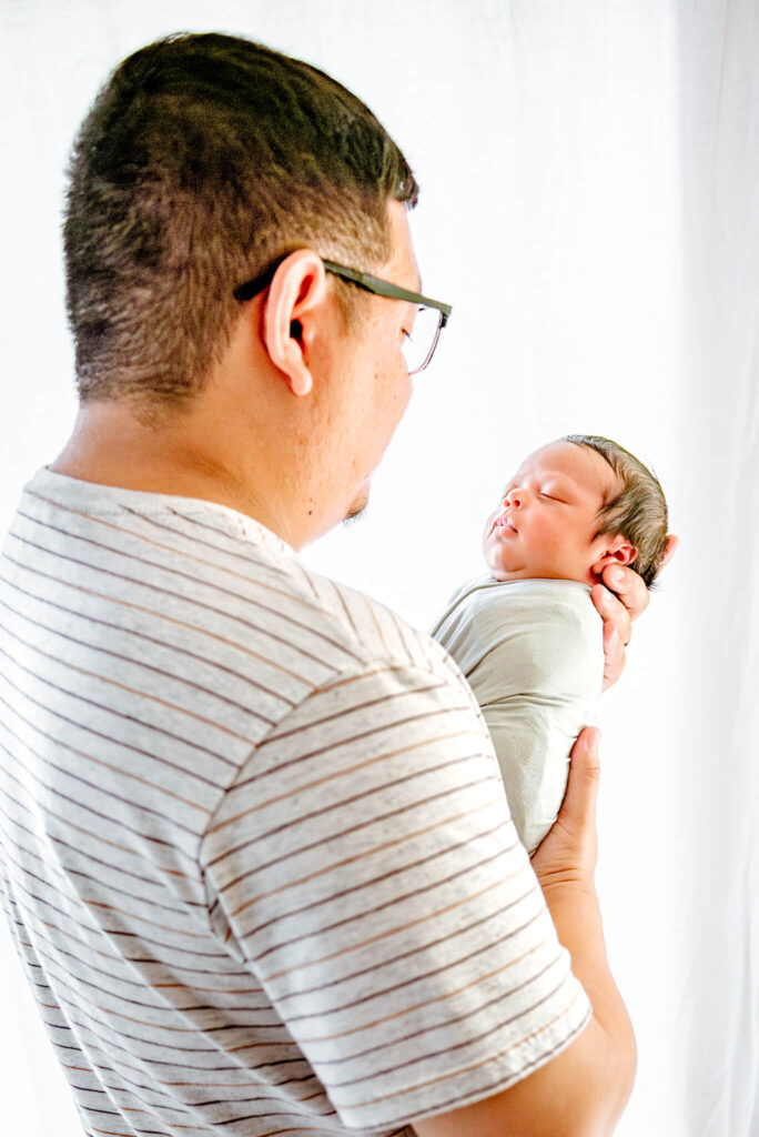 dad holding newborn son visiting lactation consultants