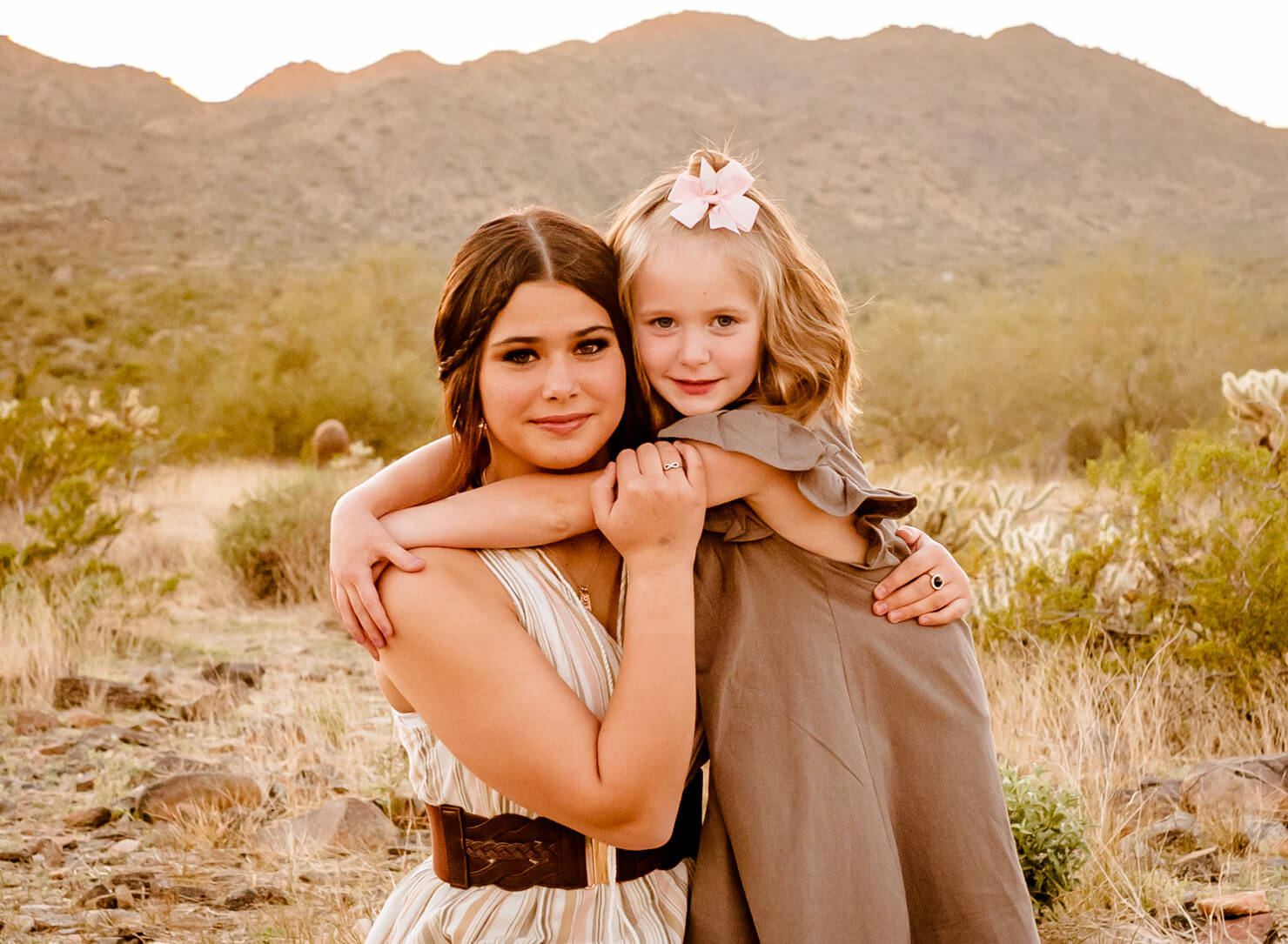 Older sister with hair done from one of the hair salons in surprise az, hugging young sister