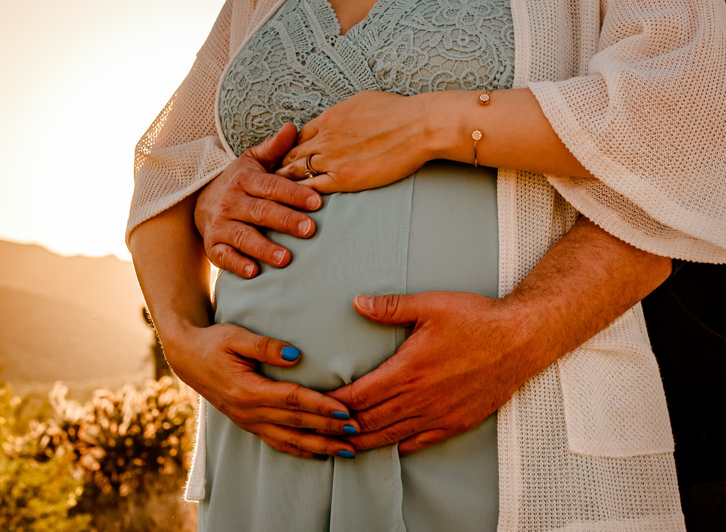 hands of parents-to-be who used a midwife in arizona, on mom's belly