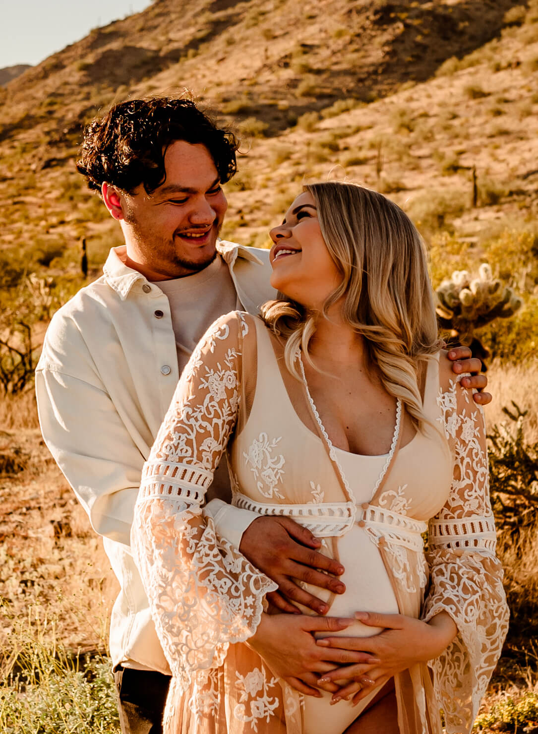 parents to be hugging for maternity portraits while talking about their arizona midwife search