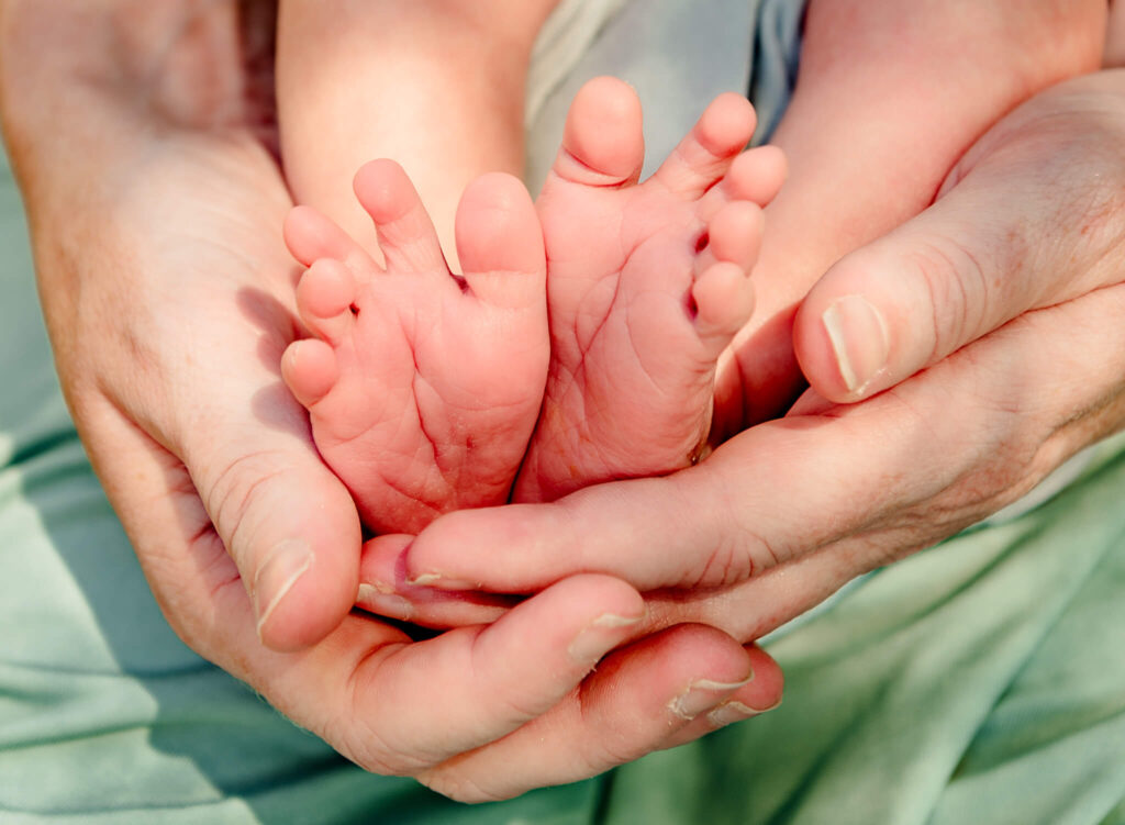 mom holding newborn feet for cast with maternity keepsake in Arizona