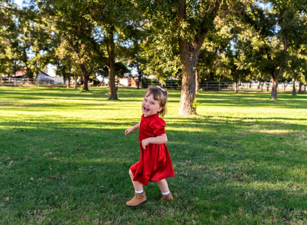 girl running through an orchard during the season for apple picking in Phoenix AZ
