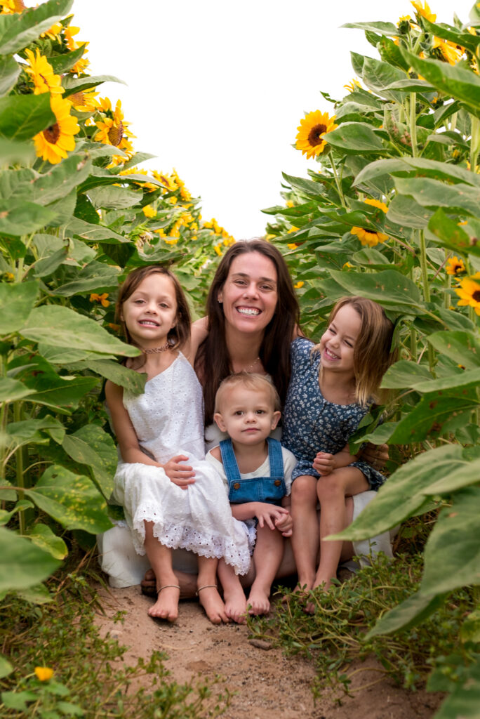 mother in flower fields near orchard for apple picking in phoenix AZ with her daughters