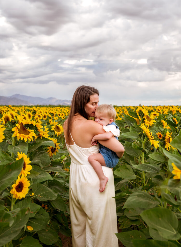 mother hugging child amid sunflowers near corn maze in Phoenix, AZ