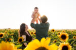 dad holding baby next to wife in sunflower field at fall festivals in phoenix, AZ