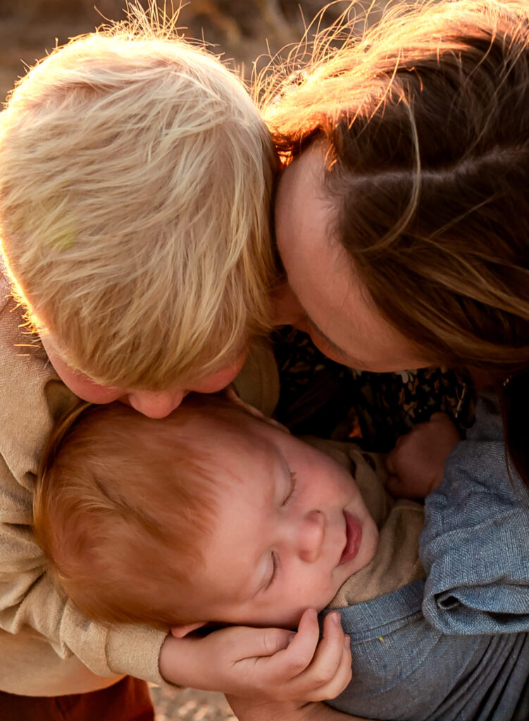mom and sons snuggling close in the cold while visiting christmas tree farm in arizona
