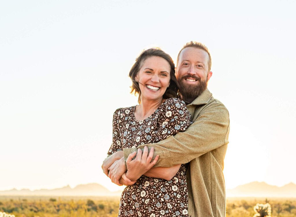 parents hugging close for a portrait at Christmas tree farm in the off season